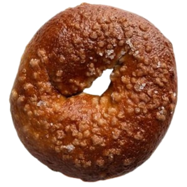 Close-up of a dark brown Ugly Bagel with a rough, bubbly texture and visible salt crystals.