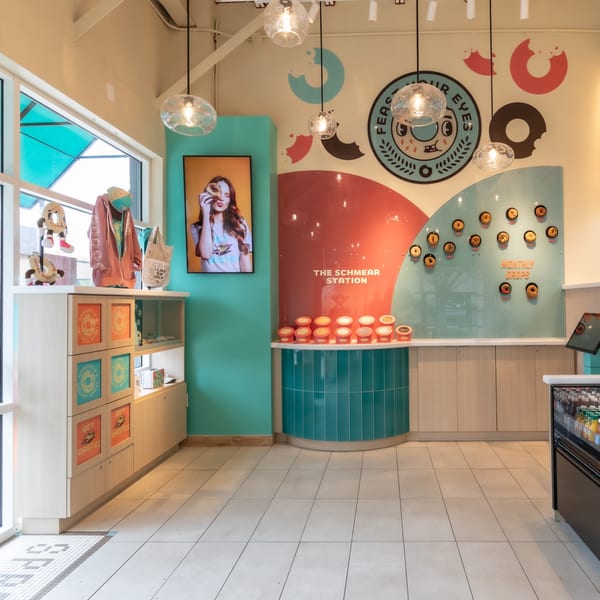 Ugly Bagel interior with a "Schmear Station," bagel displays, and branded merchandise.