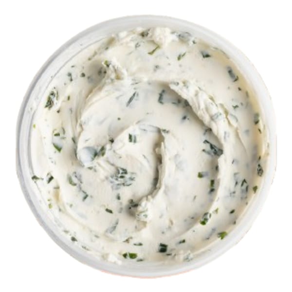 Overhead view of a container of Ugly Bagel's creamy white cream cheese with green herbs.