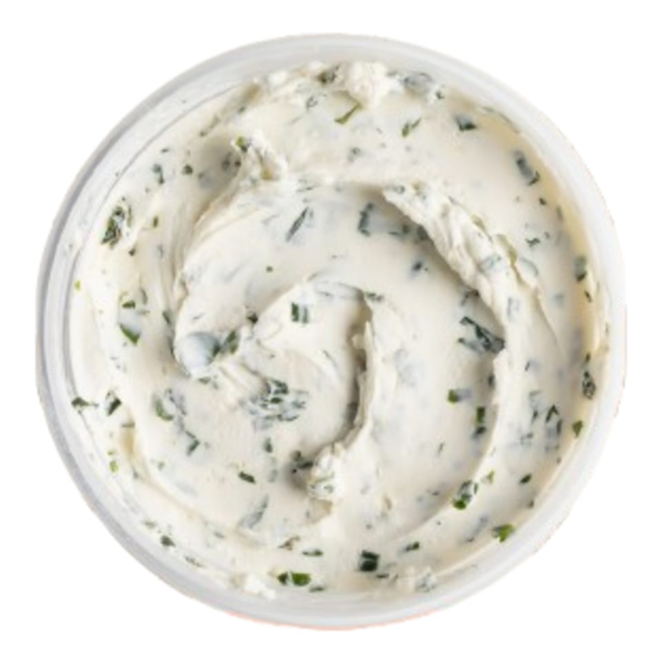 Overhead view of a container of Ugly Bagel's creamy white cream cheese with green herbs.